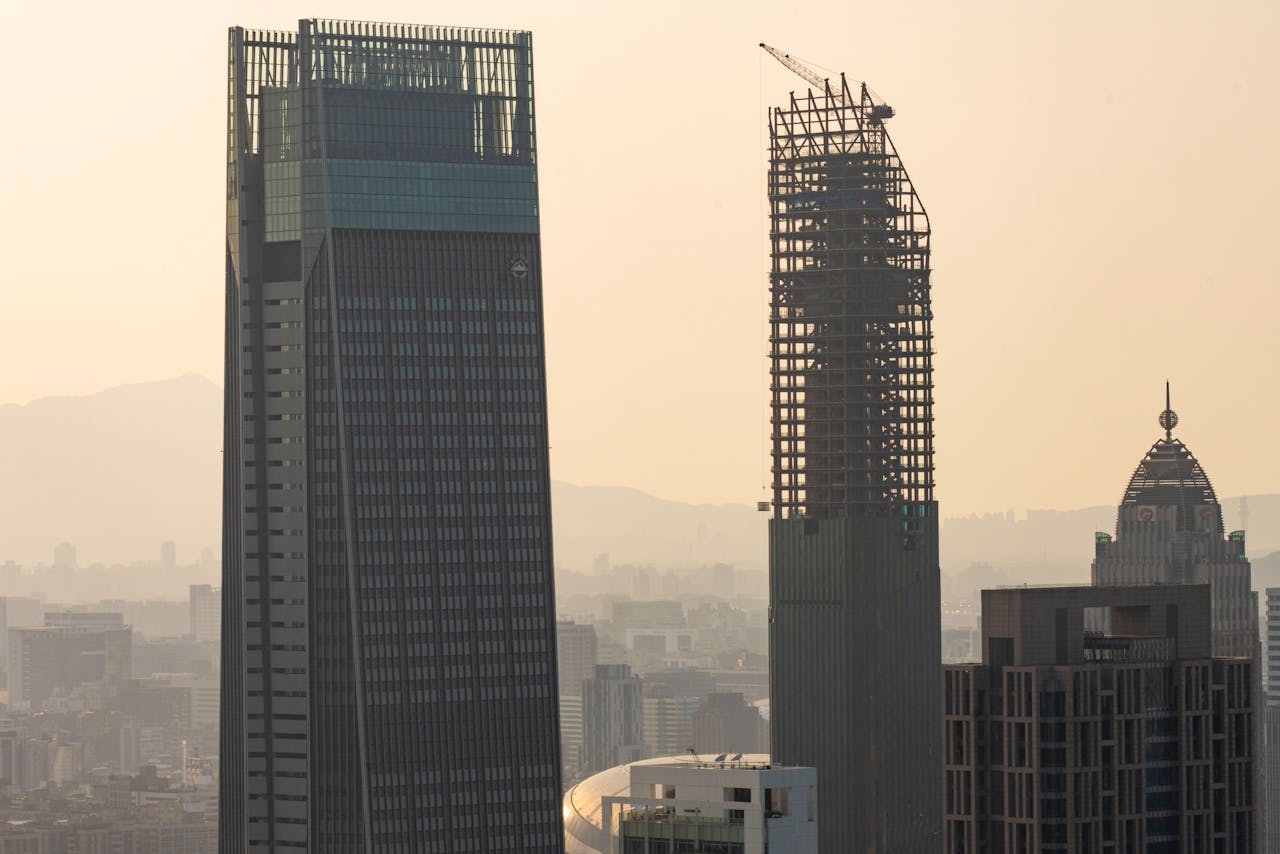 Aerial view of skyscrapers under construction amidst a city skyline at dusk.