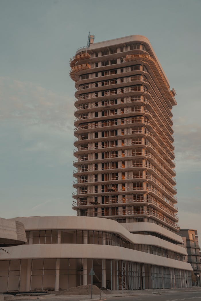 A tall, modern building under construction with a focus on balconies and structure.